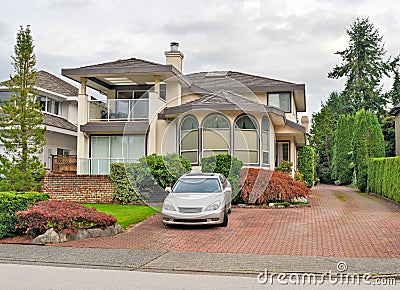 Big residential house with a car parked on pawed drvieway in front Stock Photo