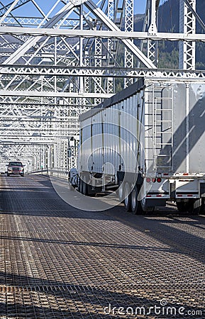 Big rig orange semi truck carry bulk semi trailer driving on win Stock Photo