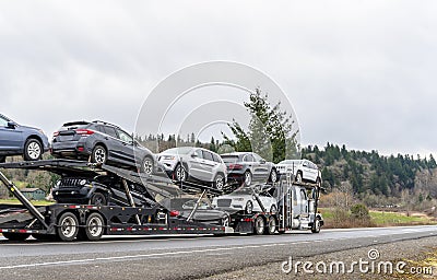 Big rig car hauler semi truck transporting cars on special two level modular semi trailer Stock Photo