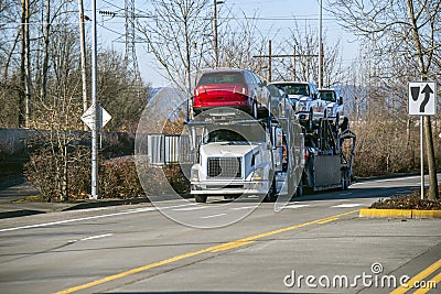 Big rig car hauler semi truck transporting cars on two levels semi trailer driving on divided road Editorial Stock Photo