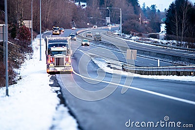 Big rig semi truck with semi trailer standing on the highway exit in snow winter weather Stock Photo