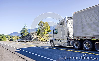 Big rig white bonnet long haul semi truck transporting frozen food in refrigerator semi trailer running on the road in Columbia Stock Photo