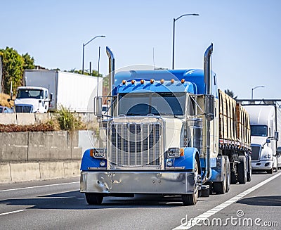 Big rigs classic semi trucks transporting cargo in different semi trailer running on the highway road with another traffic Stock Photo