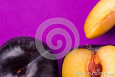 Big ripe organic purple plum whole with cut out segment wedge vivid violet background. Yellow flesh pit close up. Creative trendy Stock Photo