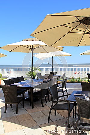 Big shade umbrellas over dining tables on outdoor patio at the beach Stock Photo