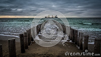 Big ship crossing the wooden pier during cloudy weather at the beach in Vlissingen, Zeeland, Holland, Netherlands Stock Photo