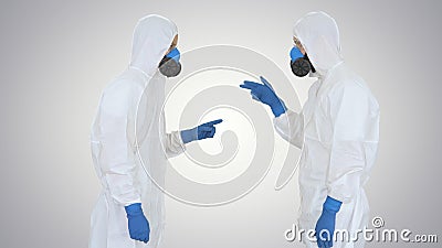 Doctors or scientists in hazamat suits meet and shake hands on gradient background. Stock Photo