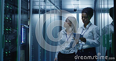 Two women are working in a data center with rows of server racks Stock Photo