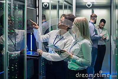 Two women are working in a data center with rows of server racks Stock Photo