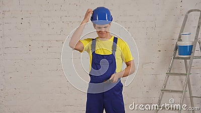 Medium shot of a young construction worker standing in the room under renovation, scratching his head, deciding which Stock Photo