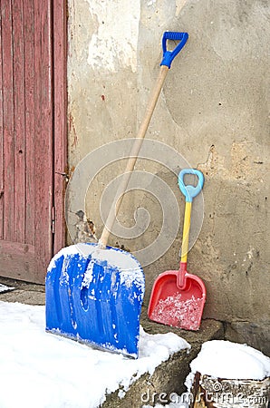 Big and small father and child snow shovels near wall Stock Photo