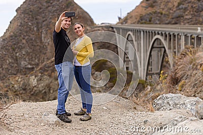 A young couple take a selfie in fron of the Big Creek Bridge, Big Sur, California, USA Editorial Stock Photo