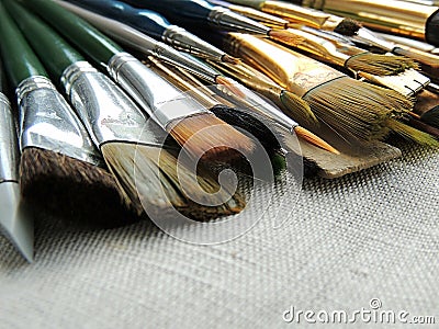Big variety of brushes, tools for painting and sculpture on linen fabric background. Stock Photo