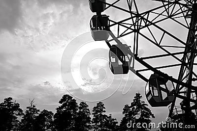 Monochrome photo. Big wheel in the city park at sunset. Rest in the amusement park Stock Photo