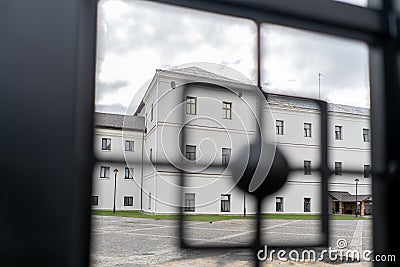 Big white Building and low sun shining seen through the gate. View through fence Stock Photo