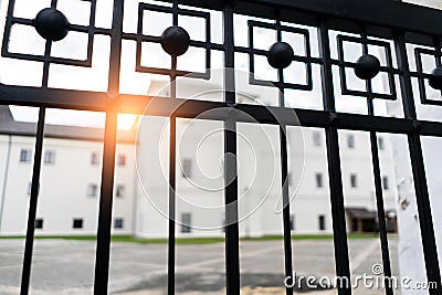 Big white Building and low sun shining seen through the gate. View through fence Stock Photo