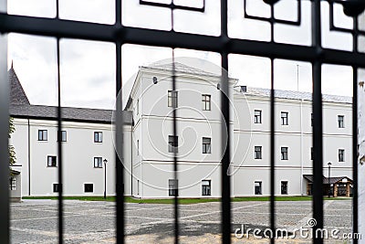 Big white Building and low sun shining seen through the gate. View through fence Stock Photo