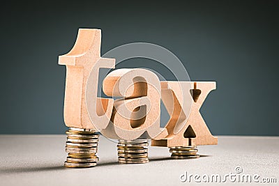 TAX word on a small heap coins, Tax Burden Stock Photo