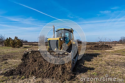 A big yellow bulldozer pushes the ground and makes a new road Stock Photo