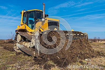 A big yellow bulldozer pushes the ground and makes a new road Stock Photo