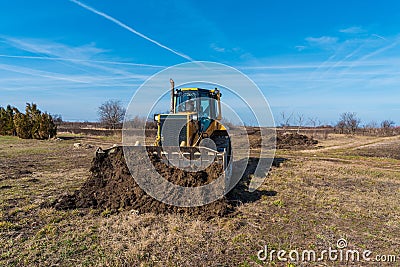A big yellow bulldozer pushes the ground and makes a new road Stock Photo