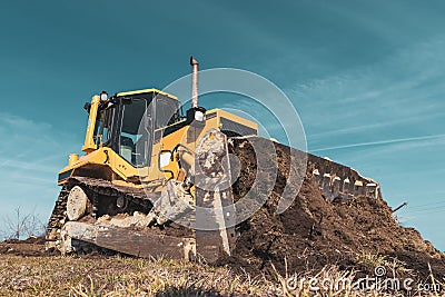 A big yellow bulldozer pushes the ground and makes a new road Stock Photo