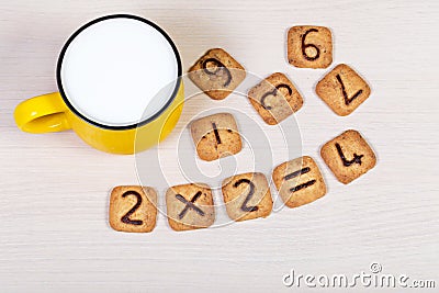 Big yellow cup of milk and funny cookies with numbers on light wooden background. Healthy breakfast for a child. Stock Photo