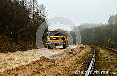 Big yellow diesel quarry dumper at work. Heavy mining truck transporting sand and clay. Editorial Stock Photo