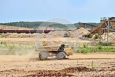 Big yellow dump truck transporting sand in an open-pit mining quarry. Editorial Stock Photo