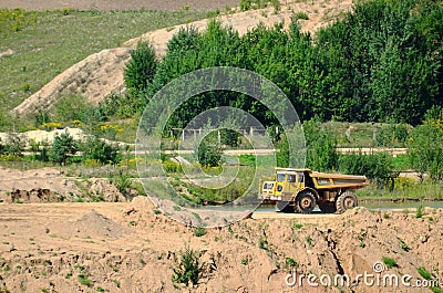 Big yellow dump truck transporting stone and gravel in an sand open-pit. Editorial Stock Photo