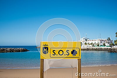 Big yellow Sos emergency sign in empty spanish beach on a sunny summer day with nobody on the beach Stock Photo
