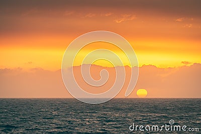 Big yellow sun falling behind the sea Stock Photo