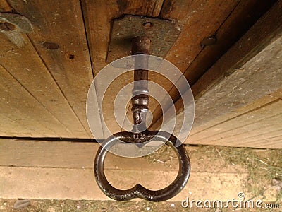 Bigger old worn black shiny key in oak wooden dusty cellar door, close-up from above, in daylight Stock Photo