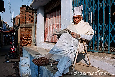 BIHAR, INDIA: Elderly asian man reads a newspaper outdoor at the evening Editorial Stock Photo
