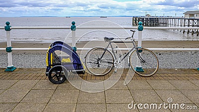 Bike with child cycle trailer, secured to railing on the sea fro Stock Photo