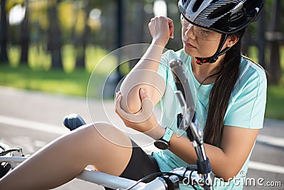 Bike injuries. Woman cyclist fell off road bike while cycling. Bicycle accident, injured elbow Stock Photo