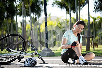 Bike injuries. Young woman cyclist fell fell off road bike while cycling. Bicycle accident, injured knee Stock Photo