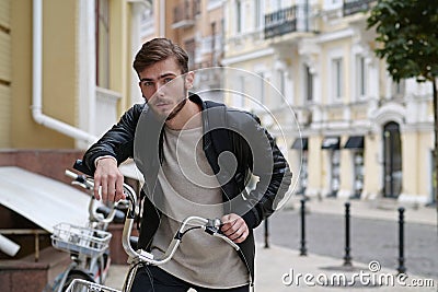 Bike messenger with backpack stands near bicycle and look at camera Stock Photo