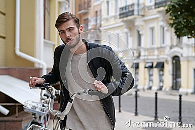 Bike messenger with backpack stands near bicycle and look at camera Stock Photo