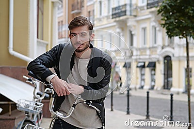 Bike messenger with backpack stands near bicycle and look at the camera Stock Photo