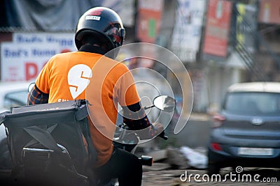 bike rider with helmet and a swiggy tshirt showing the rapid growth of food delivery e-commerce startups unicorns Editorial Stock Photo