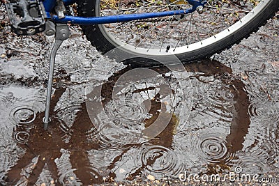 Bike Tire and Kickstand in Puddle with Raindrops. Stock Photo