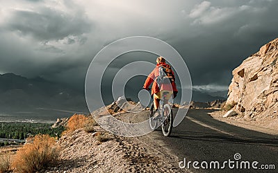 Bike tourist rides on Himalaya mountain road on way to buddist monastery Stock Photo
