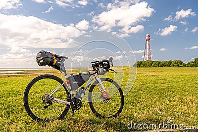 Bikepacking at the north sea, view on the lighthouse of campen near emden with a packed gravel bike in front, north sea, germany Editorial Stock Photo