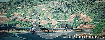 Biker on a classic motorcycle greeting while riding on a winding road Stock Photo