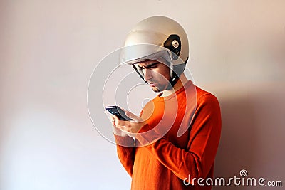 Biker dressed in orange looking at his mobile phone Stock Photo