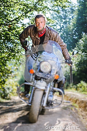 Biker driving his cruiser motorcycle on road in the forest Stock Photo