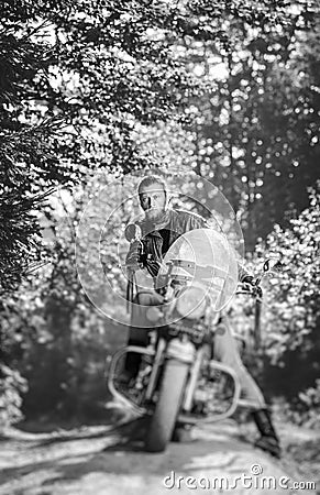 Biker driving his cruiser motorcycle on road in the forest Stock Photo