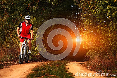 Biker on the forest road riding outdoor Stock Photo