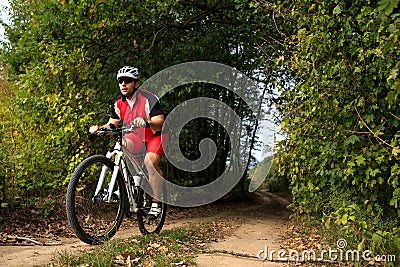 Biker on the forest road riding outdoor Stock Photo